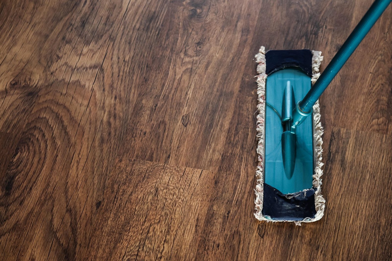 A teal mop on a wood floor