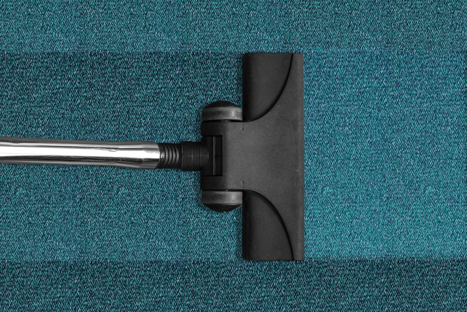 A vacuum head on a teal carpet